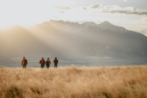 Four hunters walking with mountain in background